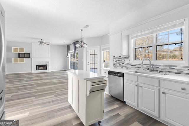 1484 Highland Bluff Ct, Suwanee, GA 30024 - kitchen with light countertops, a sink, tasteful backsplash, stainless steel dishwasher, and ceiling fan with notable chandelier
