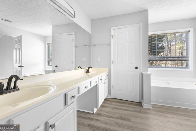 1484 Highland Bluff Ct, Suwanee, GA 30024 - full bathroom featuring a sink, a garden tub, wood finished floors, a textured ceiling, and visible vents