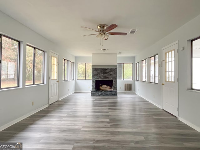 1105 Claxton Dairy Rd, Dublin, GA 31021 - unfurnished living room featuring a ceiling fan, wood finished floors, a stone fireplace, and baseboards
