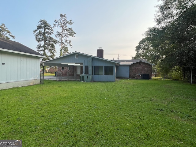 1105 Claxton Dairy Rd, Dublin, GA 31021 - back of house featuring a chimney, a sunroom, a carport, and central AC