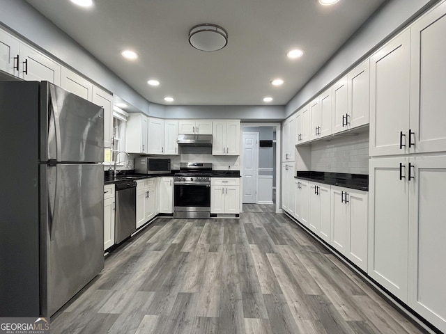 1105 Claxton Dairy Rd, Dublin, GA 31021 - kitchen with appliances with stainless steel finishes, under cabinet range hood, dark countertops, recessed lighting, and wood finished floors