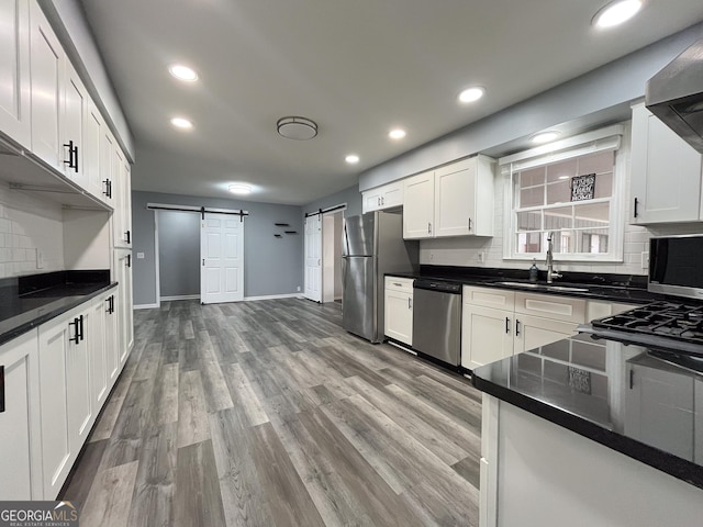 1105 Claxton Dairy Rd, Dublin, GA 31021 - kitchen featuring stainless steel appliances, a barn door, a sink, white cabinetry, and tasteful backsplash