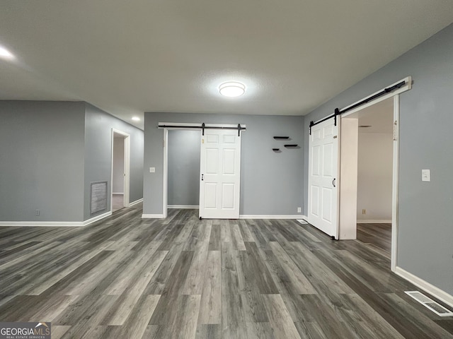 1105 Claxton Dairy Rd, Dublin, GA 31021 - unfurnished bedroom featuring a barn door, baseboards, and dark wood-style flooring