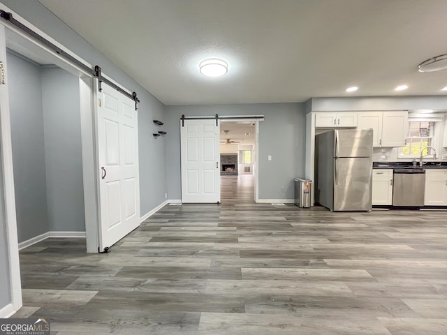 1105 Claxton Dairy Rd, Dublin, GA 31021 - kitchen with a barn door, appliances with stainless steel finishes, baseboards, light wood-style flooring, and recessed lighting