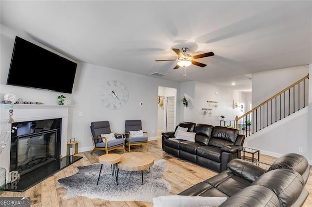 197 Saddleridge Dr, Bremen, GA 30110 - living room with stairway, a glass covered fireplace, a ceiling fan, and wood finished floors