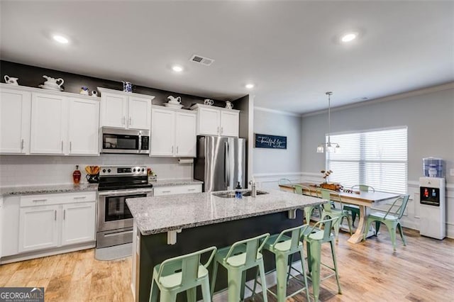 197 Saddleridge Dr, Bremen, GA 30110 - kitchen with appliances with stainless steel finishes, white cabinets, ornamental molding, light stone countertops, and an island with sink