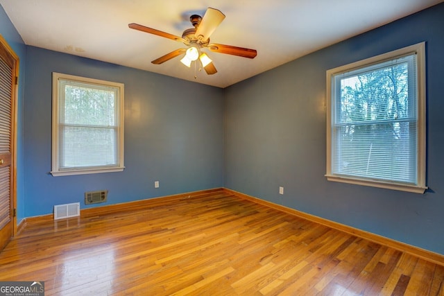 spare room with baseboards, ceiling fan, visible vents, and hardwood / wood-style flooring