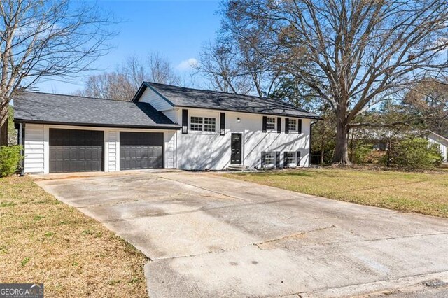 view of front of house with an attached garage, concrete driveway, and a front yard