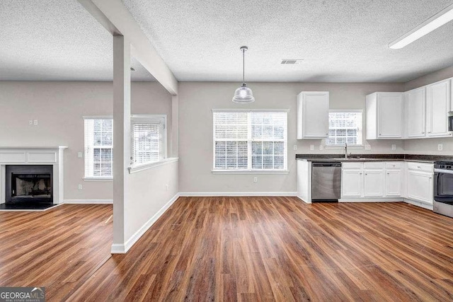 4970 Wewatta St SW, Atlanta, GA 30331 - kitchen featuring stainless steel appliances, wood finished floors, dark countertops, a textured ceiling, and white cabinetry