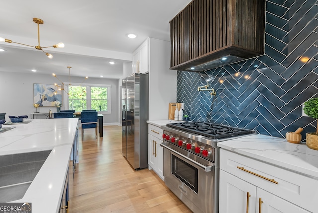 kitchen with light stone countertops, white cabinetry, backsplash, and appliances with stainless steel finishes