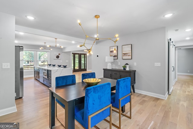 dining space with french doors, baseboards, and light wood-style floors