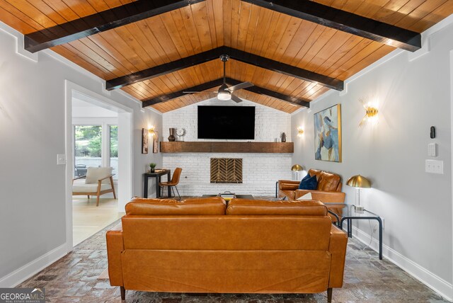 living room with baseboards, stone tile flooring, a fireplace, and ceiling fan