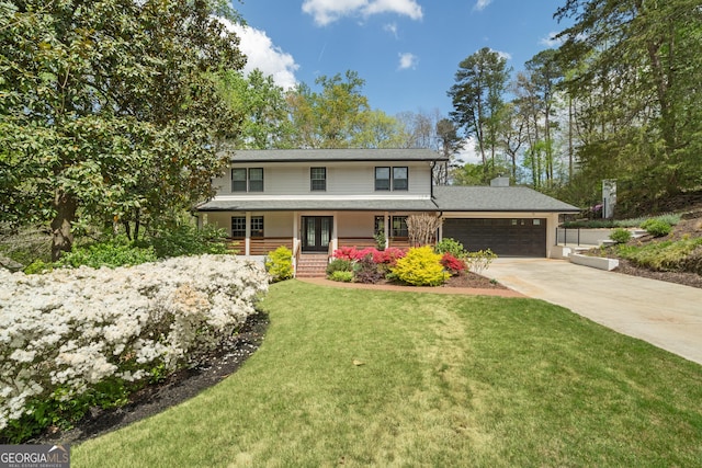 traditional-style home featuring a front lawn, driveway, french doors, an attached garage, and a porch