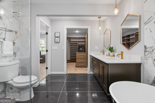 bathroom with marble finish floor, toilet, a sink, and double vanity