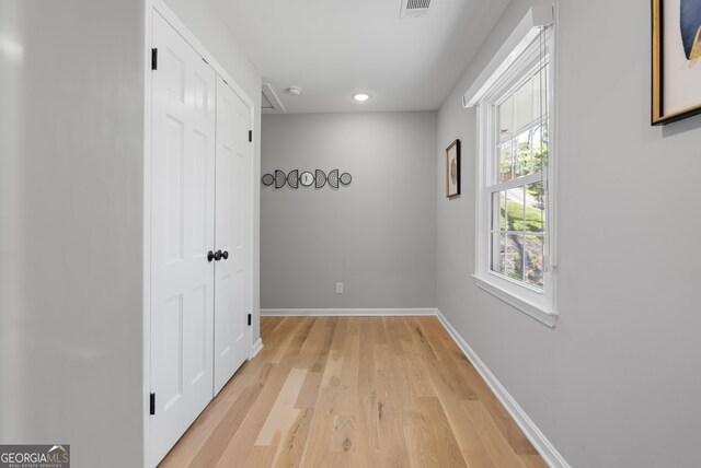 hallway with visible vents, light wood-style flooring, baseboards, and recessed lighting