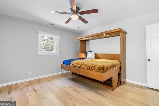 bedroom with baseboards, a ceiling fan, visible vents, and light wood-style flooring