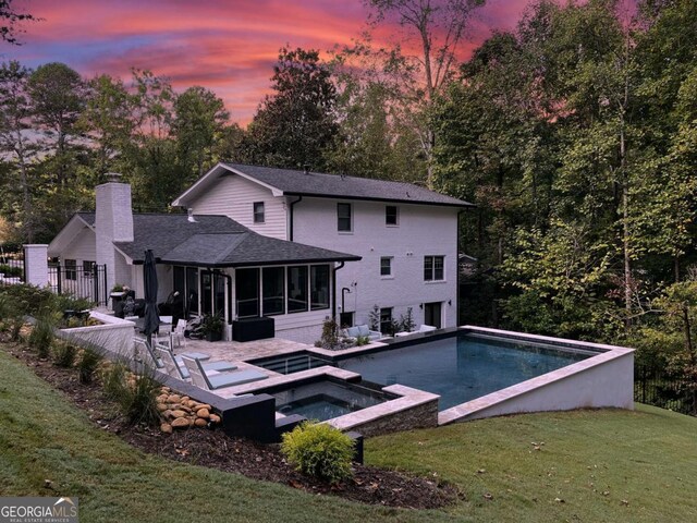 rear view of property featuring a chimney, fence, a lawn, a sunroom, and a patio