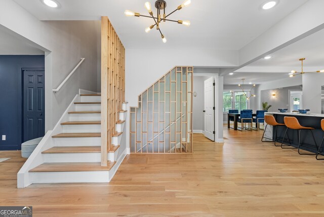stairway featuring baseboards, wood finished floors, a chandelier, and recessed lighting