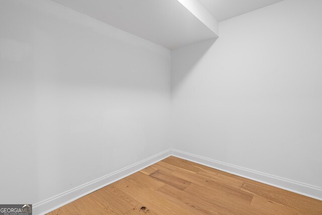 spare room with baseboards and light wood-style floors