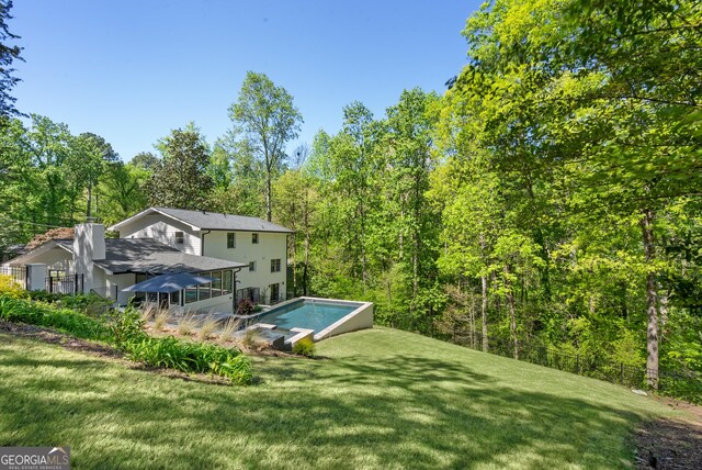 pool with a yard and a wooded view