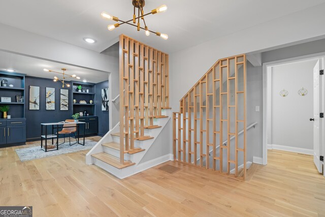 stairway featuring baseboards, wood finished floors, and a notable chandelier
