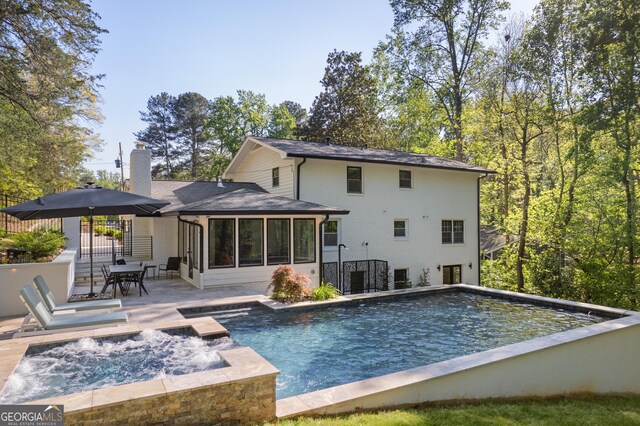 back of house with a chimney, an outdoor pool, a shingled roof, a patio, and a sunroom