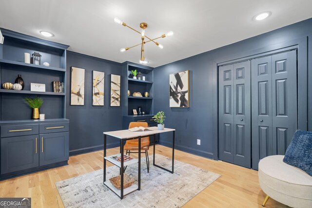 office area with light wood finished floors, a notable chandelier, and built in shelves