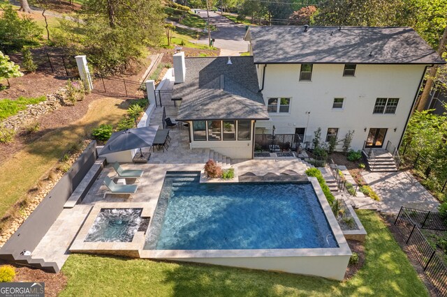 rear view of house featuring roof with shingles, a fenced backyard, a patio area, a sunroom, and an in ground hot tub