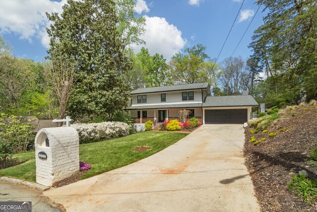 traditional home featuring a chimney, an attached garage, driveway, covered porch, and a front yard