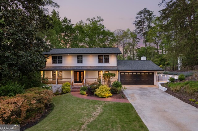 traditional-style house featuring driveway, french doors, a porch, a front yard, and a garage