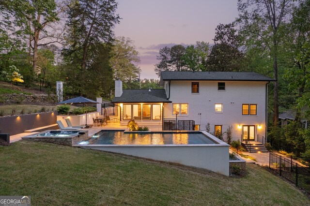 back of house featuring a fenced in pool, a chimney, fence, a yard, and an in ground hot tub