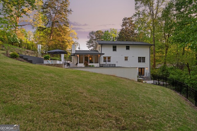 back of property with a chimney, fence, and a lawn