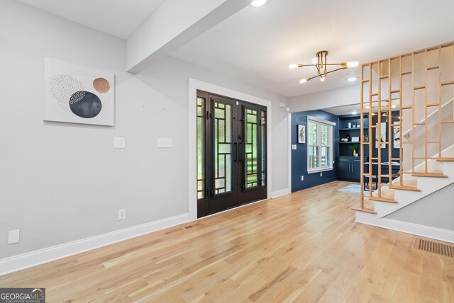 foyer entrance with visible vents, baseboards, a notable chandelier, wood finished floors, and stairway