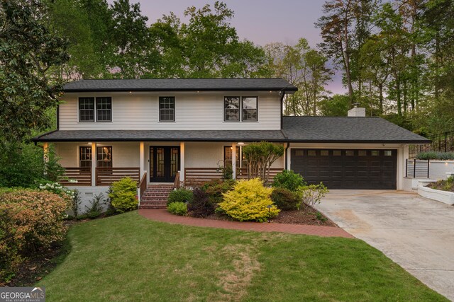 view of front of home with concrete driveway, a chimney, a lawn, a porch, and a garage