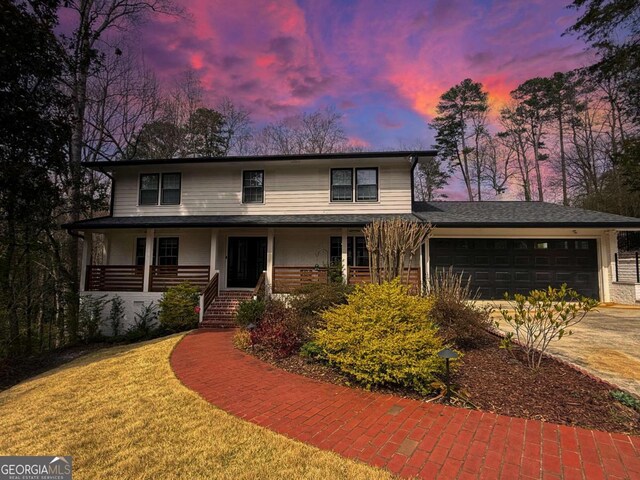 view of front of property featuring a porch, concrete driveway, and a garage