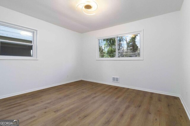 unfurnished room featuring wood finished floors, baseboards, and visible vents