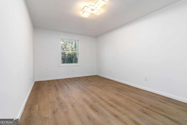 spare room with baseboards and wood finished floors
