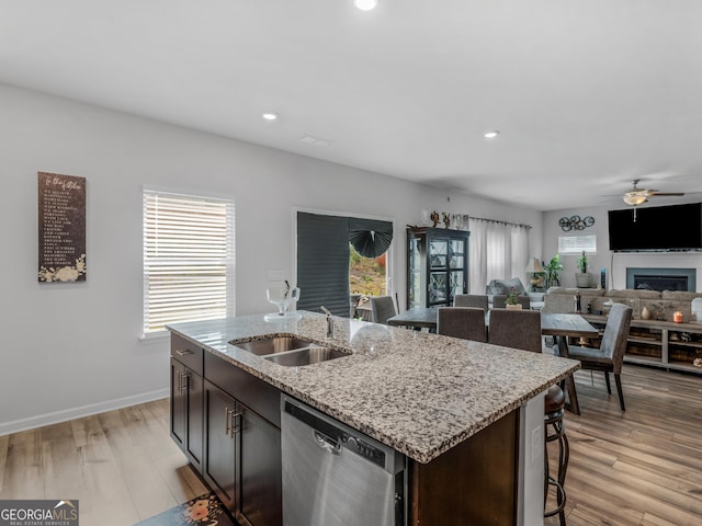 kitchen featuring light wood finished floors, a breakfast bar, dishwasher, ceiling fan, and a sink
