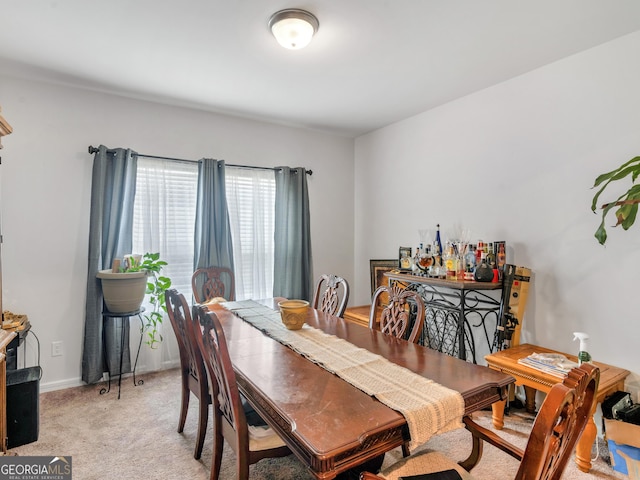 dining area featuring light carpet and baseboards