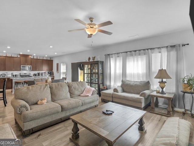 living room with light wood-style flooring, a wealth of natural light, and ceiling fan