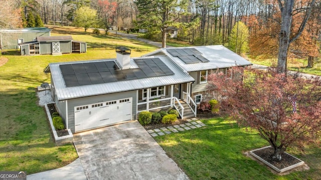 view of front of property with metal roof, a chimney, concrete driveway, a front yard, and a porch