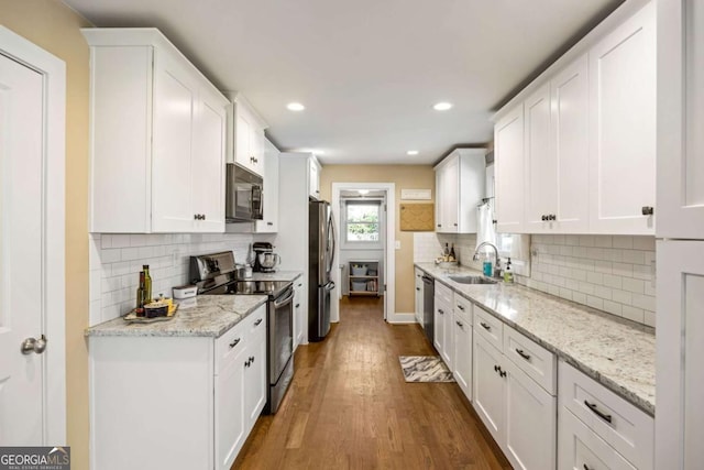 kitchen featuring white cabinetry, a sink, stainless steel appliances, and wood finished floors