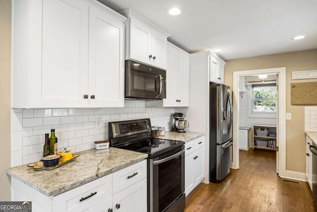 kitchen with backsplash, light stone countertops, appliances with stainless steel finishes, white cabinets, and dark wood-type flooring