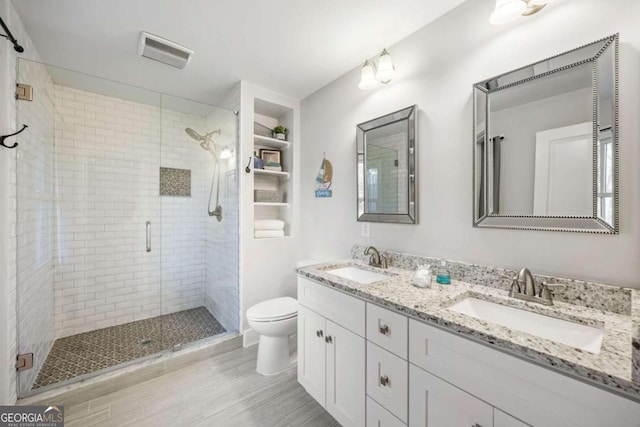 bathroom featuring visible vents, a sink, toilet, and a stall shower