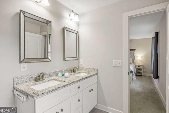 full bath with baseboards, double vanity, and a sink
