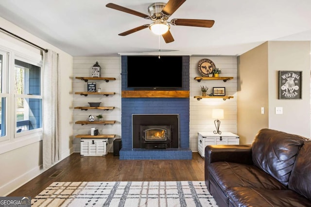 living room with a ceiling fan, visible vents, baseboards, and wood finished floors