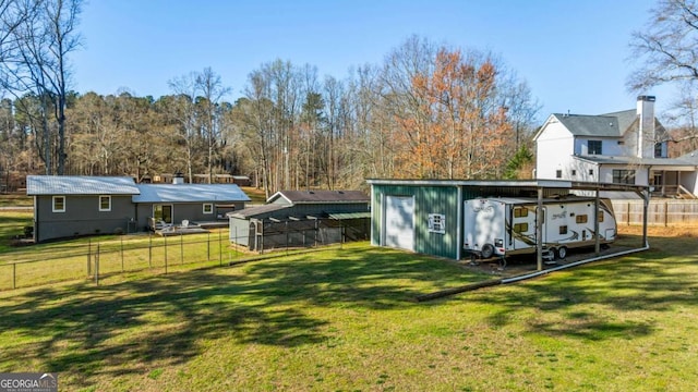 view of yard with an outdoor structure, a carport, and fence