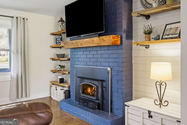 living area with baseboards, a fireplace, and wood finished floors