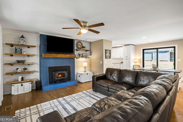 living area featuring visible vents, wood finished floors, a fireplace, and a ceiling fan
