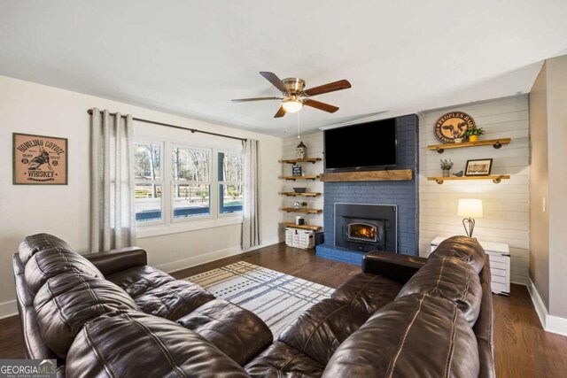 living area featuring a ceiling fan, a brick fireplace, baseboards, and wood finished floors
